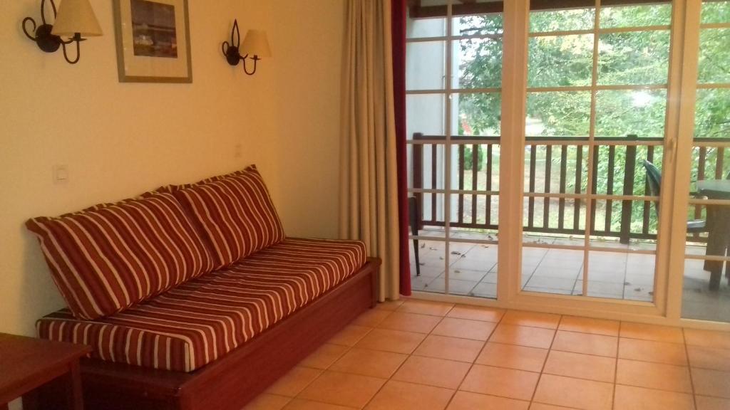 ein Wohnzimmer mit einem Sofa und einer Glasschiebetür in der Unterkunft N101, parc d'arradoy-St J P de Port in Uhart-Cize
