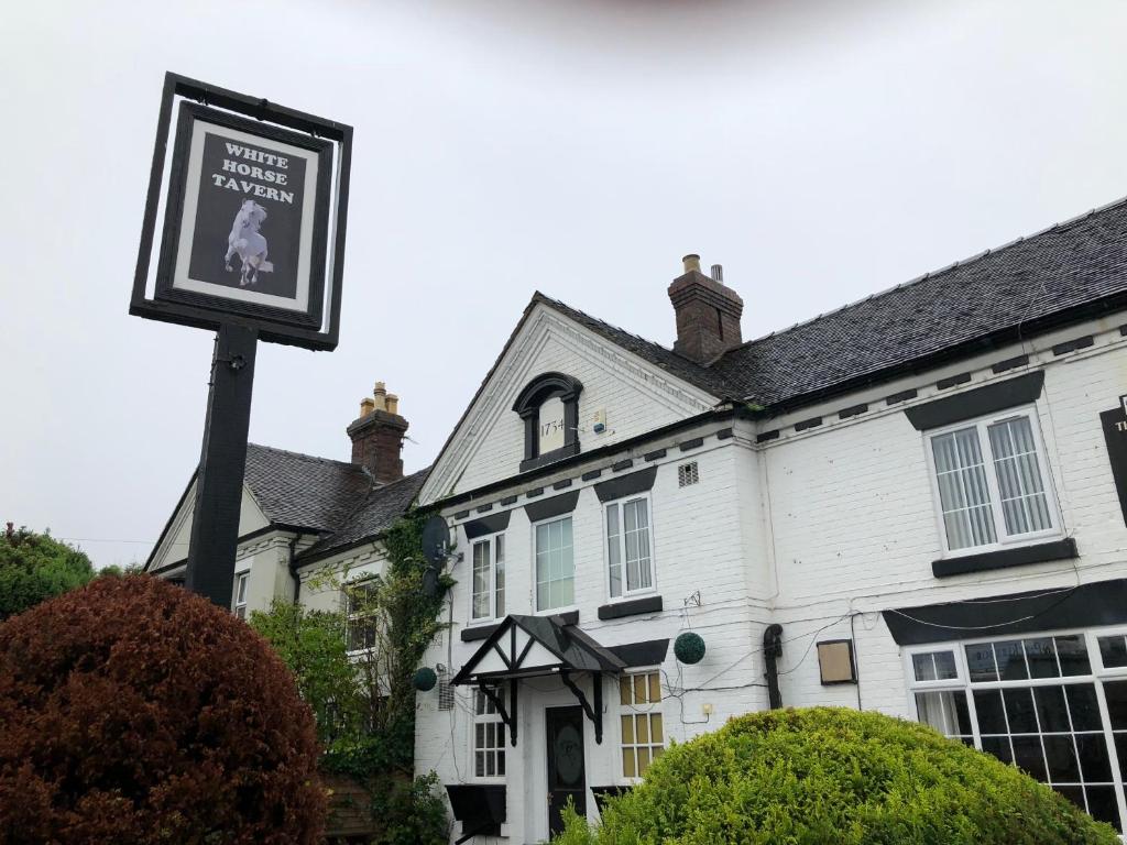 um sinal em frente a uma casa branca em White Horse Tavern em Telford