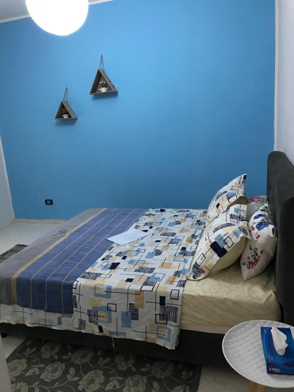 Cama en habitación con pared azul en Apartment Tunis 1 Near airport en Ariana