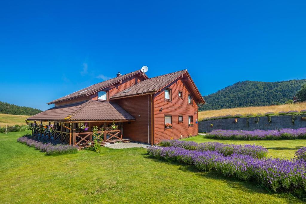 una casa in legno in un campo con fiori viola di Boutique B&B Japodi a Mrkopalj