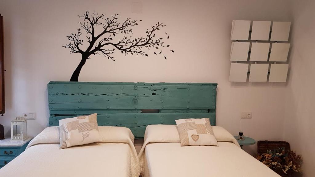 two beds in a room with a tree on the wall at El Patio De La Aljama in Córdoba