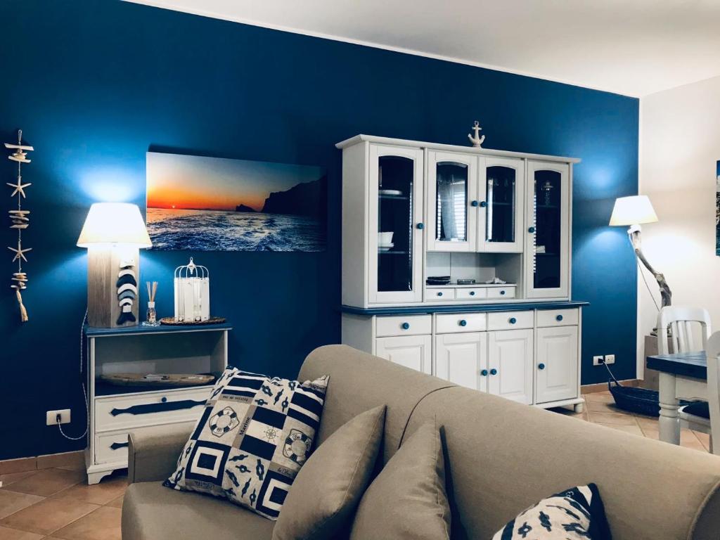 a living room with a couch and a blue wall at Appartamento BluOltreMare in San Vito lo Capo