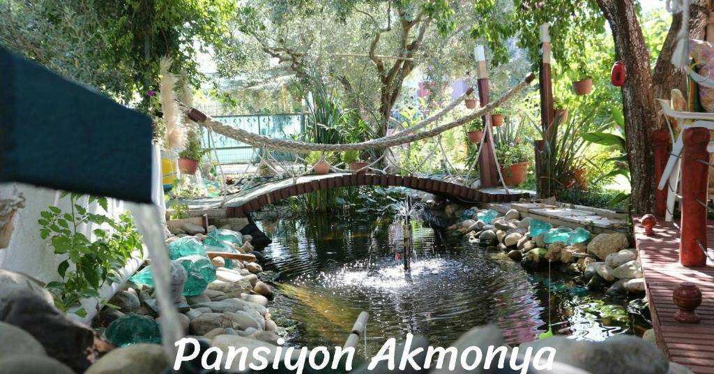 eine Brücke in einem Garten mit einem Teich in der Unterkunft Akmonya Pansiyon in Eriklice