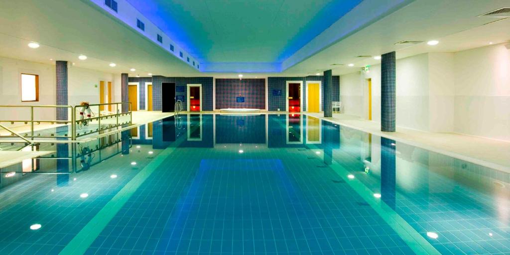 - une grande piscine avec des carreaux bleus dans un bâtiment dans l'établissement Maldron Hotel & Leisure Centre Limerick, à Limerick