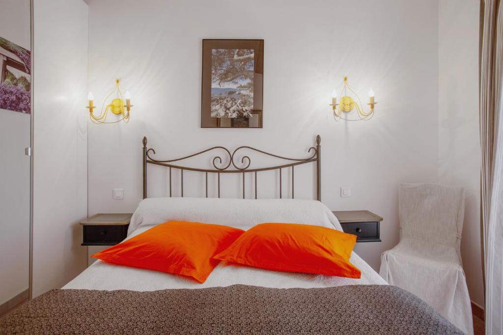 1 dormitorio con 1 cama con 2 almohadas de color naranja en coustelline, en Le Lavandou