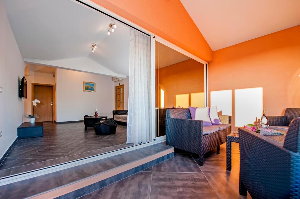 salon z pomarańczowymi ścianami i dużym oknem w obiekcie Apartments Centener w Rovinj