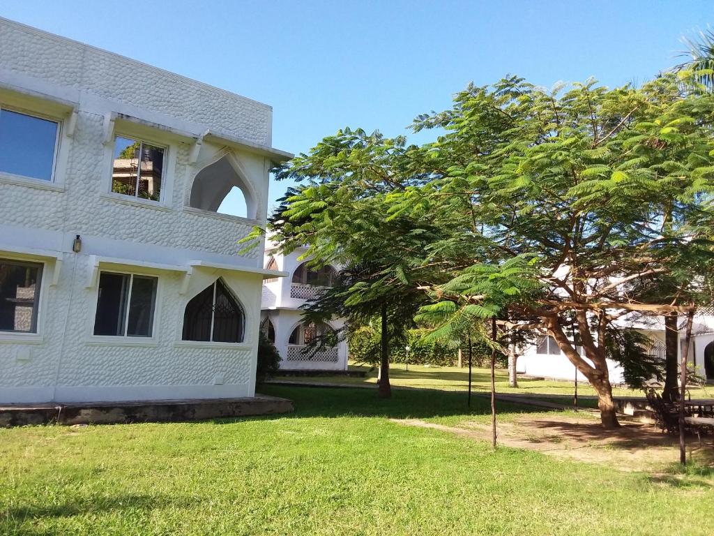 una casa blanca con un árbol en el patio en Royal Palms Apartment A4, en Mombasa
