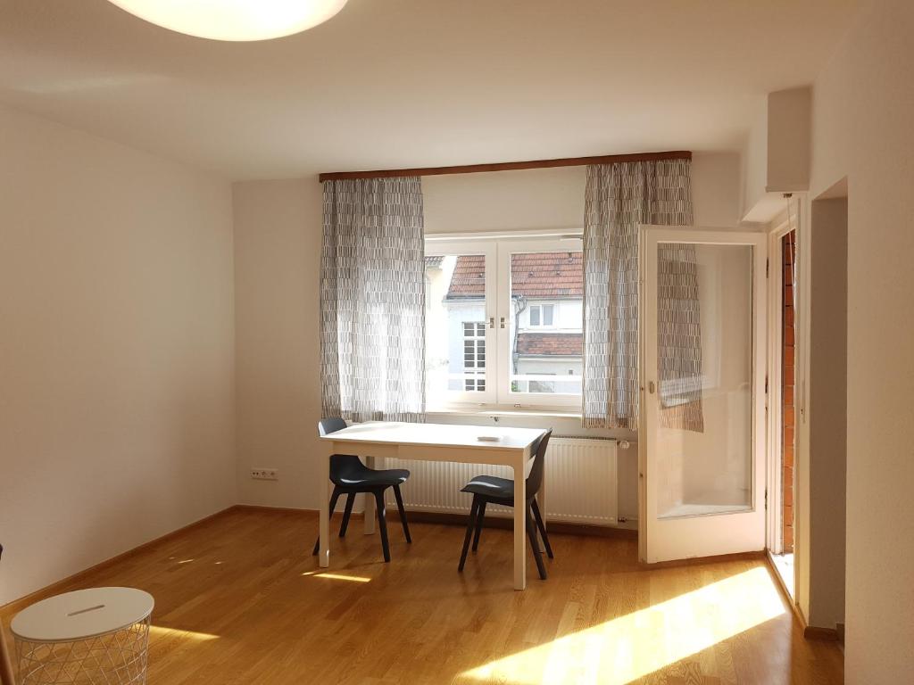 ハイデルベルクにあるWohnung am Neckarのテーブルと椅子2脚、窓が備わる客室です。