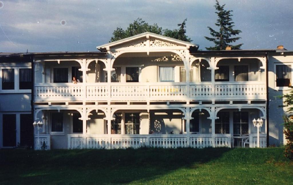 een groot wit huis met een groot balkon bij Pension Kastanienhof in Göhren
