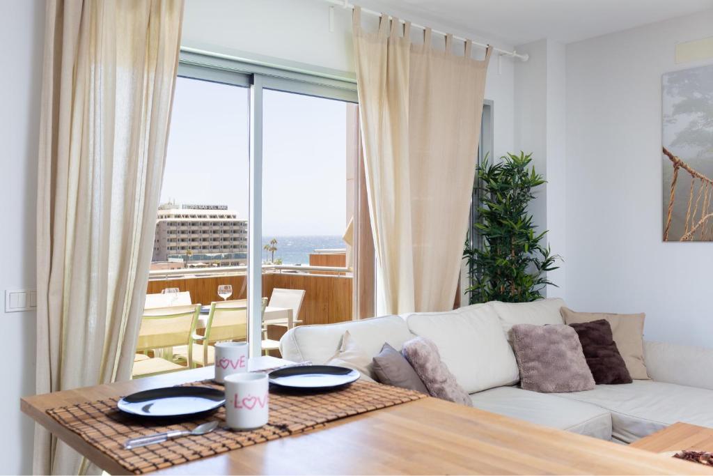 Sea View Apartment in El Médano with pool & private parking space في إل ميدانو: غرفة معيشة مع أريكة بيضاء وطاولة