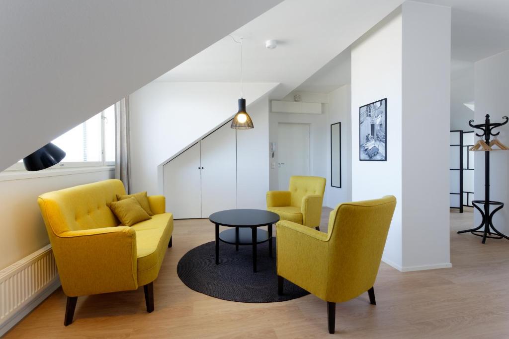 a living room with yellow chairs and a table at Forenom Serviced Apartments Helsinki Kruununhaka in Helsinki