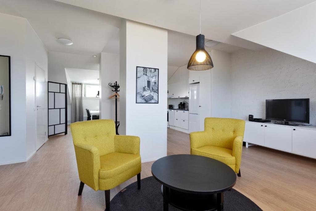 a living room with two yellow chairs and a table at Forenom Serviced Apartments Helsinki Kruununhaka in Helsinki