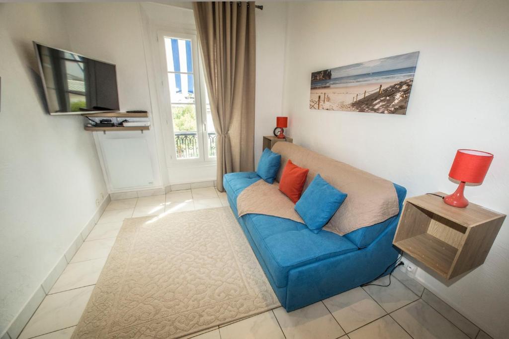 un salon avec un canapé bleu et une télévision dans l'établissement Le BLUMARINE, à Cannes