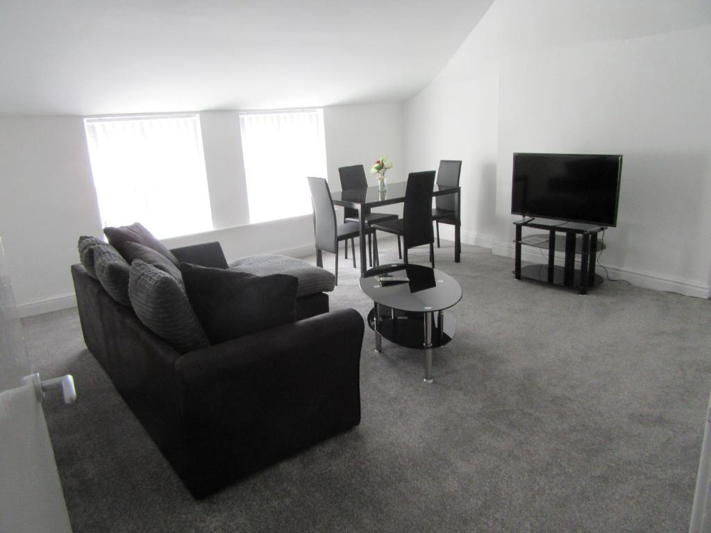 a living room with a couch and a table and a television at No 6 AT 19 IVANHOE - LARGE 2 BED NEAR SEFTON PARK AND LARK LANE in Liverpool