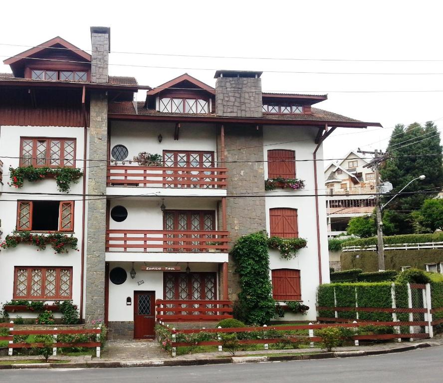 um edifício com portas vermelhas e janelas numa rua em Apto Campos do Jordão Capivari em Campos do Jordão