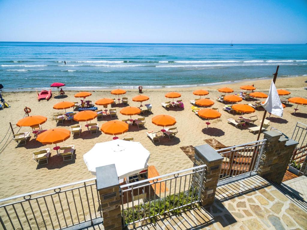 a beach with orange umbrellas and chairs and the ocean at Acciaroli Vacanze Residence in Acciaroli