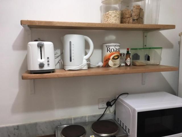 a kitchen with wooden shelves and a microwave at Parkview Brisbane in Brisbane