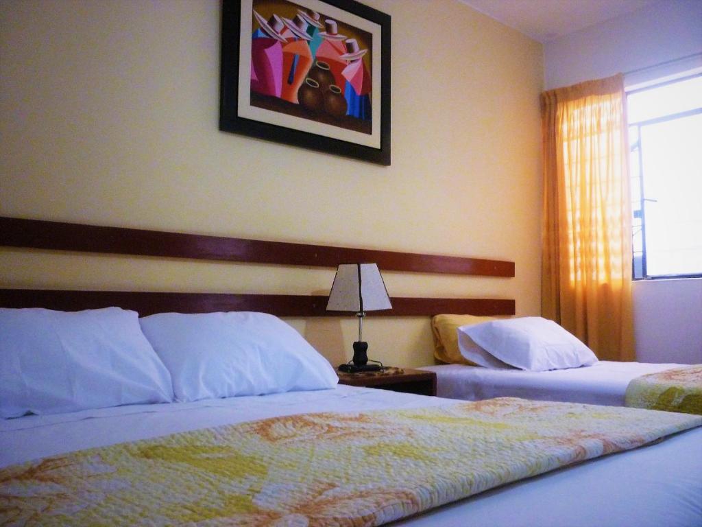 a hotel room with two beds and a picture on the wall at Anccalla Inn Guesthouse in Nazca