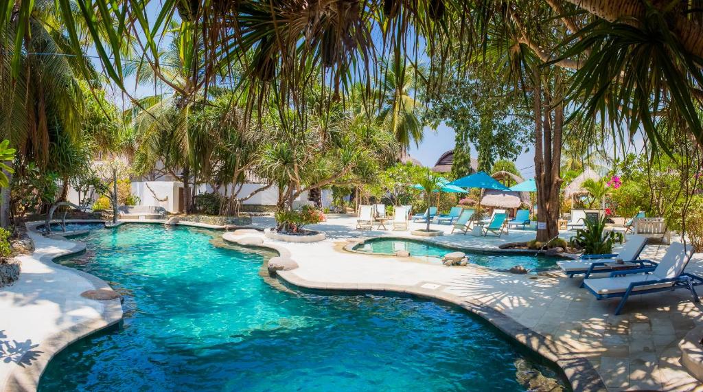 een zwembad met palmbomen en ligstoelen bij Sunrise Resort in Gili Air