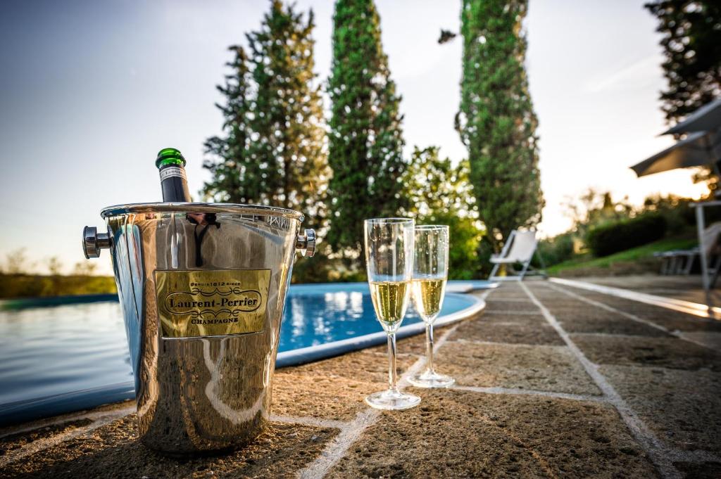 dos copas de vino sentadas en una mesa junto a una piscina en Villa Somelli, en Empoli