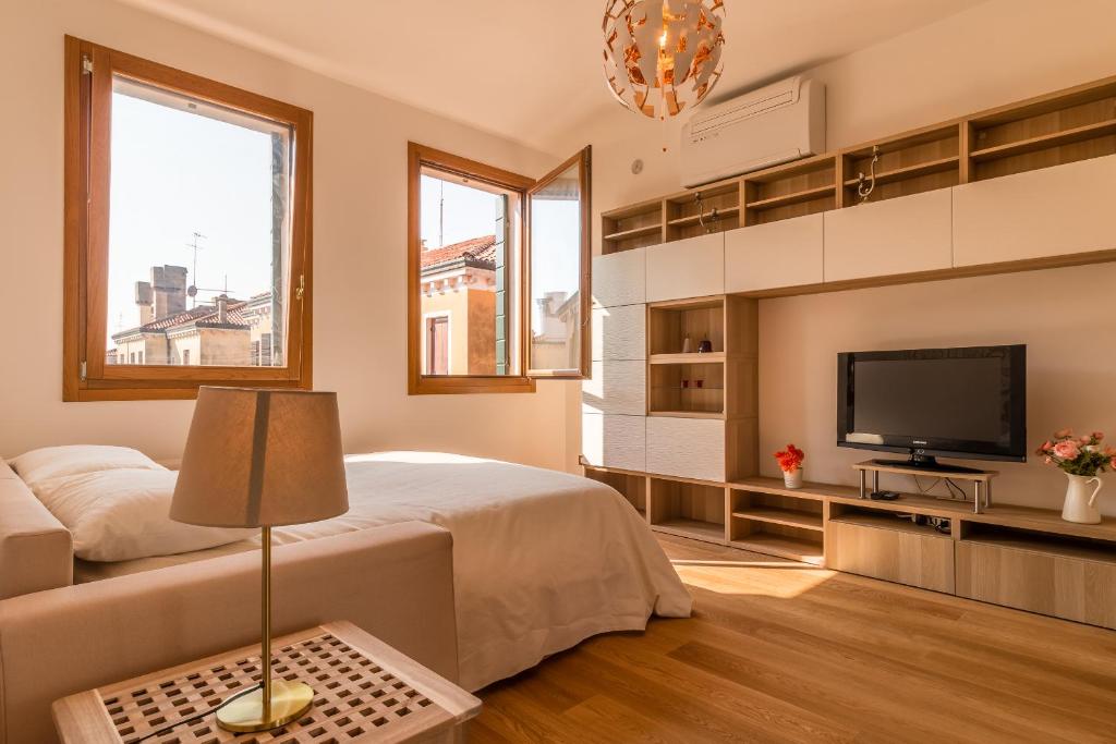 1 dormitorio con 1 cama y TV de pantalla plana en SUNNY NEST CANAL VIEW IN VENICE CHIC MOVIDA, en Venecia
