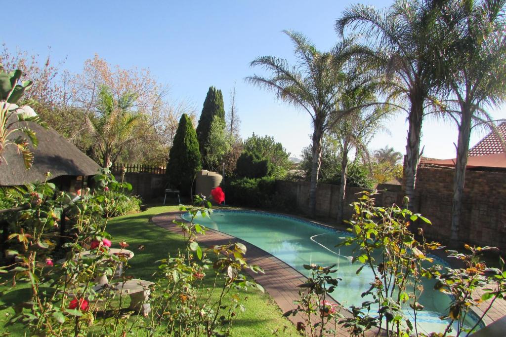 - une piscine dans une cour ornée d'arbres et de plantes dans l'établissement Oasis Of Life Guest House, à Witbank