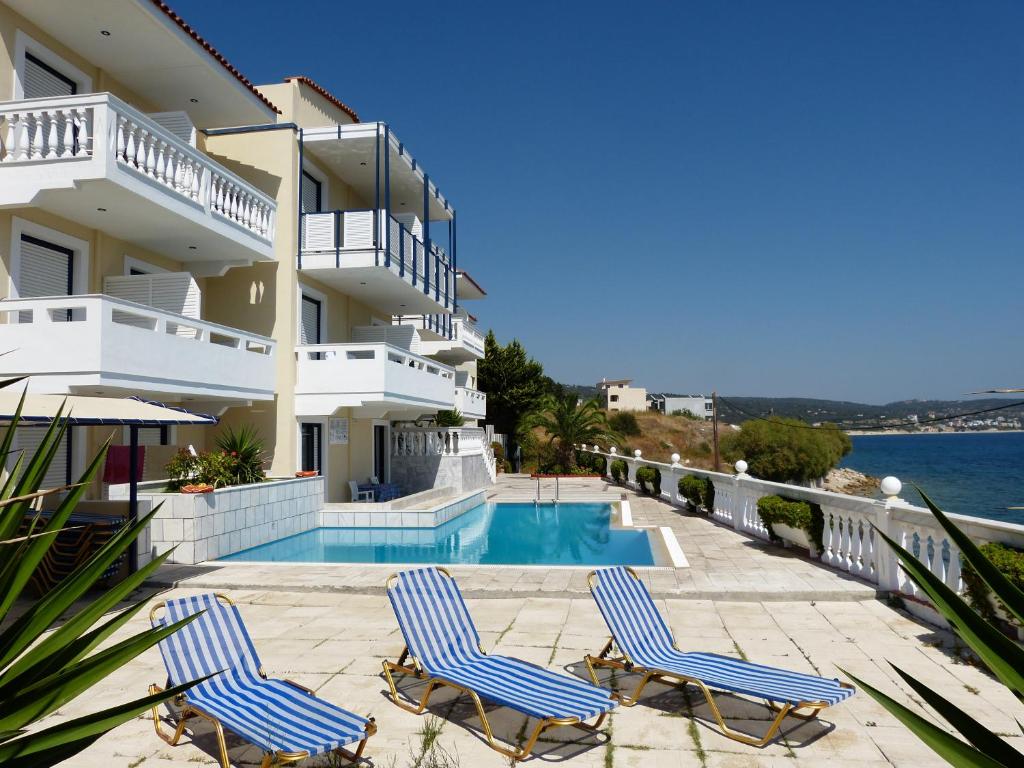 twee stoelen en een zwembad voor een gebouw bij Ostria Seaside Studios and Apartments in Katarráktis