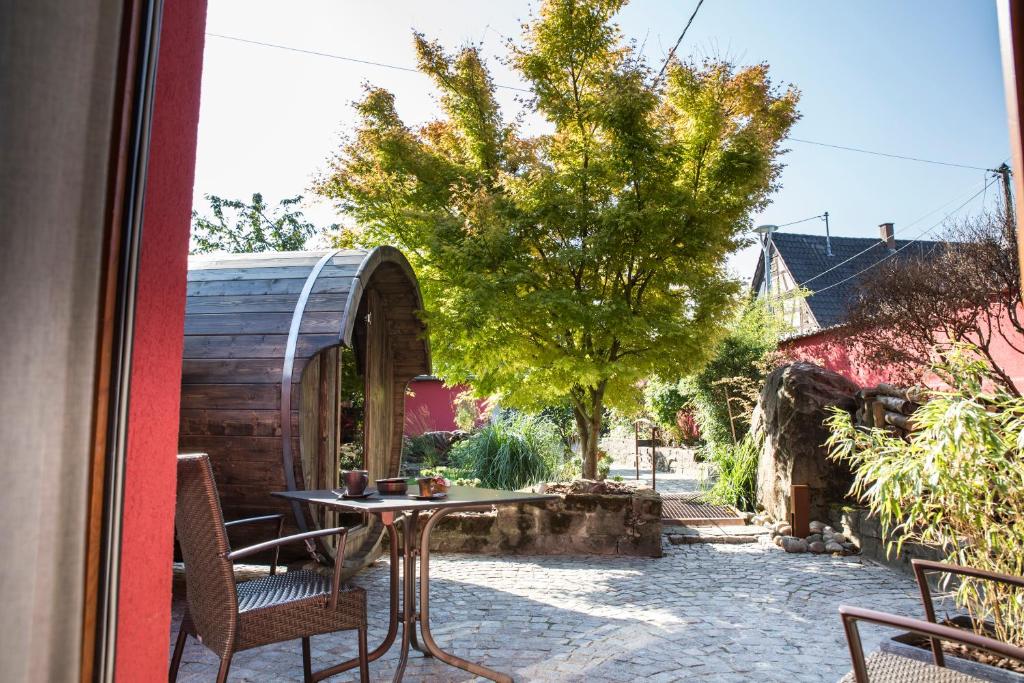 patio ze stołem, krzesłami i drzewem w obiekcie Auberge au Boeuf w mieście Sessenheim