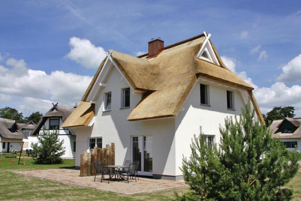 een groot wit huis met een rieten dak bij Haffmuschel in Zirchow