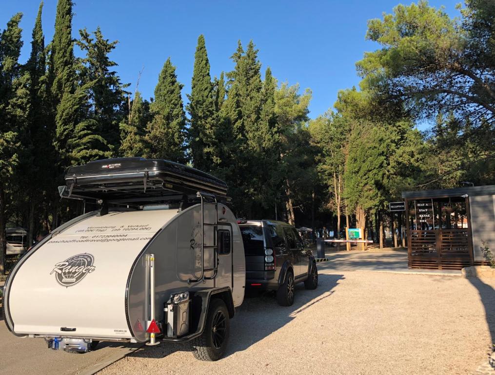 a truck with a camper parked next to a building at Camping Vransko jezero - Crkvine in Pakoštane