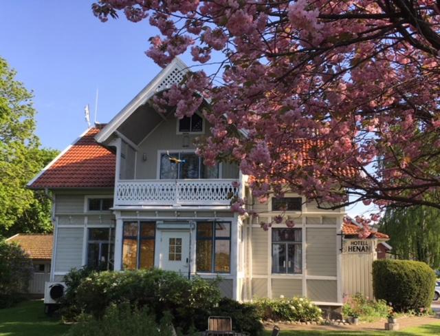 uma casa branca com uma árvore florida à frente. em Villa Frideborg em Henån