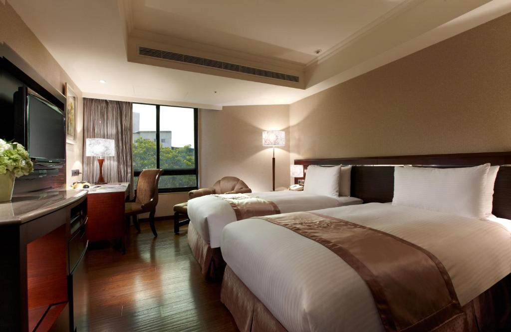 a hotel room with two beds and a television at Taichung Charming City Hotel in Taichung