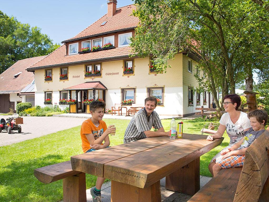 un grupo de personas sentadas en una mesa de picnic de madera en Ferienwohnung Meierhof, en Sankt Märgen