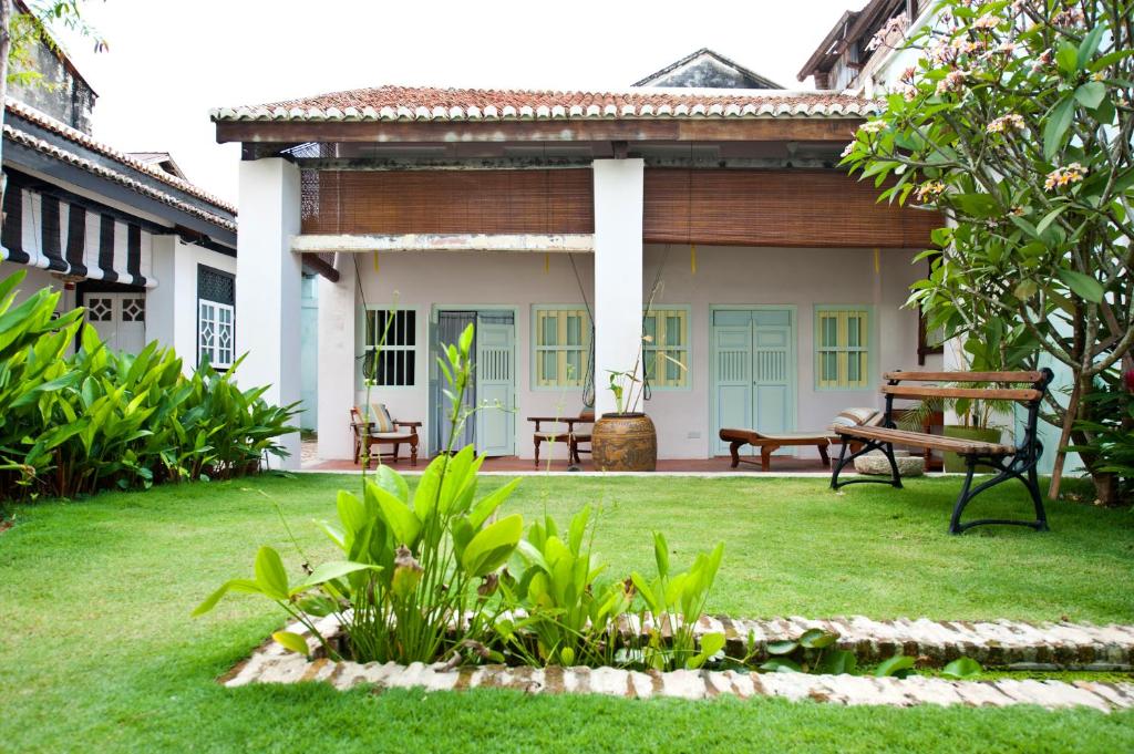 a porch of a house with a bench in the yard at 23 Love Lane Hotel in George Town