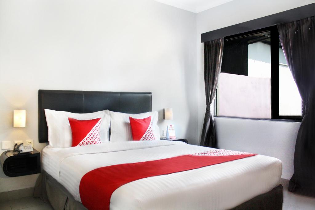 a bedroom with a large bed with red and white pillows at Super OYO Capital O 136 Manggis Inn in Jakarta