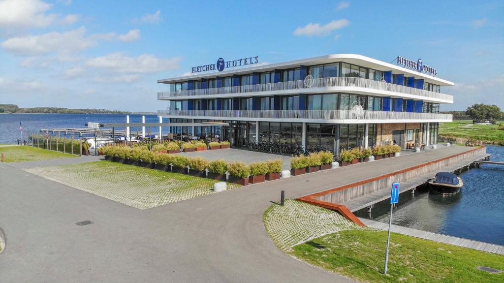 ein großes Gebäude neben einem Wasserkörper in der Unterkunft Fletcher Hotel-Restaurant Het Veerse Meer in Arnemuiden