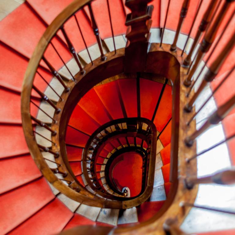 a spiral staircase in a building with red at Hôtel De La Vallée in Dinard