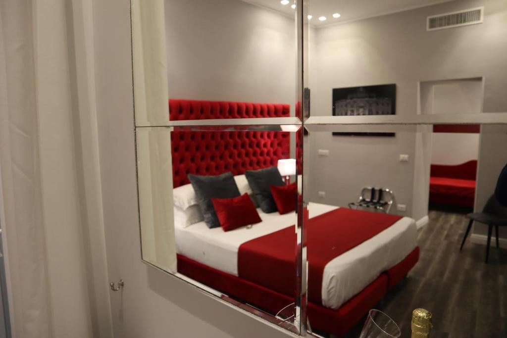 espejo que refleja un dormitorio con cama con almohadas rojas en MILLINA SUITES IN NAVONA en Roma