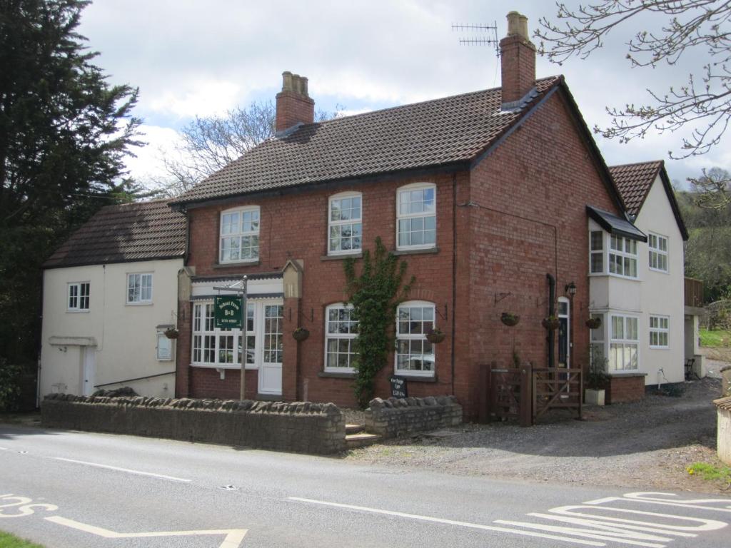 a red brick building with white windows and a street at School Farm in Blagdon