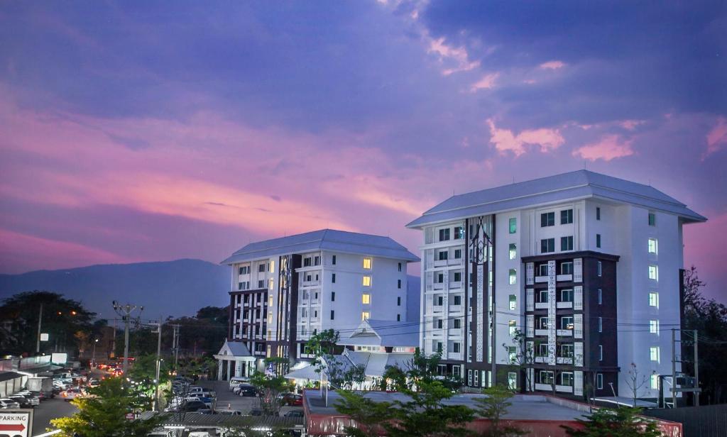 two tall white buildings in a city at dusk at At Ruam Chok Hotel in Chiang Mai