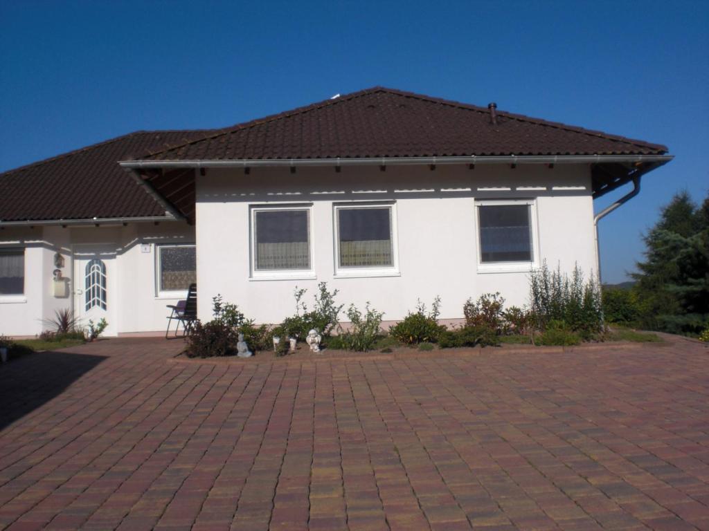 a white house with a black roof and a brick driveway at Ferienwohnung Schöne Aussicht in Diemelsee