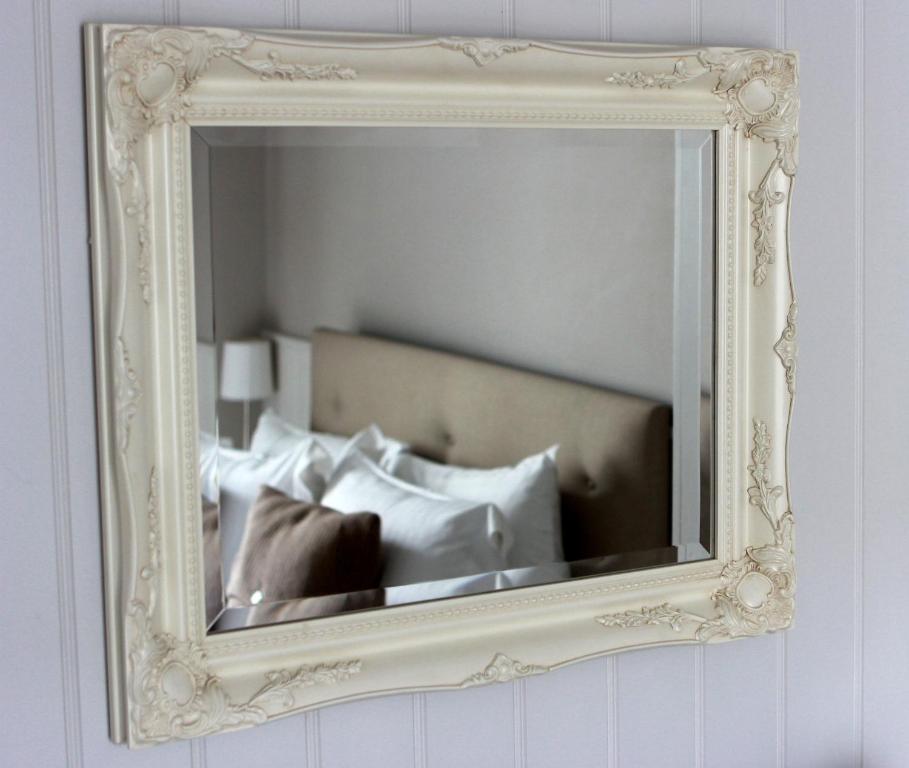 a mirror on a wall with a bed with pillows at Fox and Grapes in London
