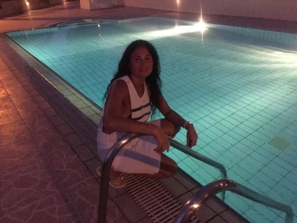 a woman sitting next to a swimming pool at night at Hermes Complex 2 Kappari Paralimni Cyprus in Paralimni