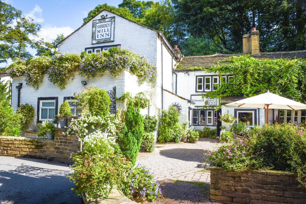 a white building with an umbrella in front of it at Shibden Mill Inn in Halifax