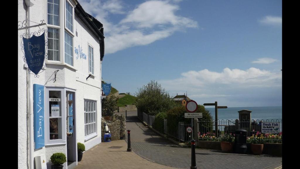 a white building on a street with a street sign at Bay View Guest House in Beer