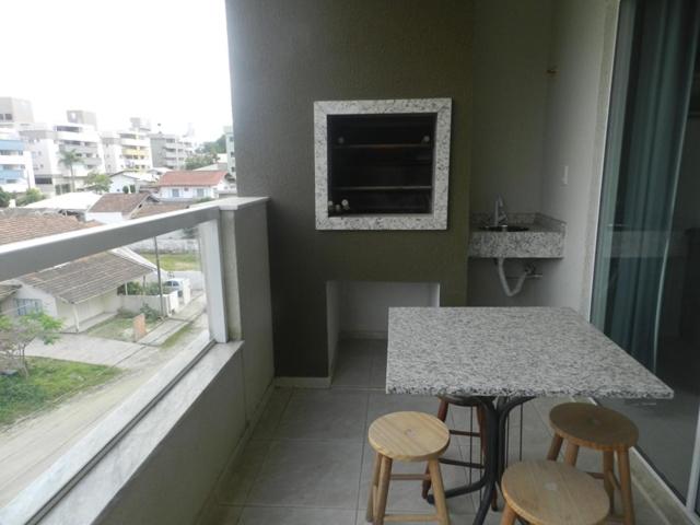cocina con mesa, 2 taburetes y ventana en Reserva Jardim, en Bombinhas