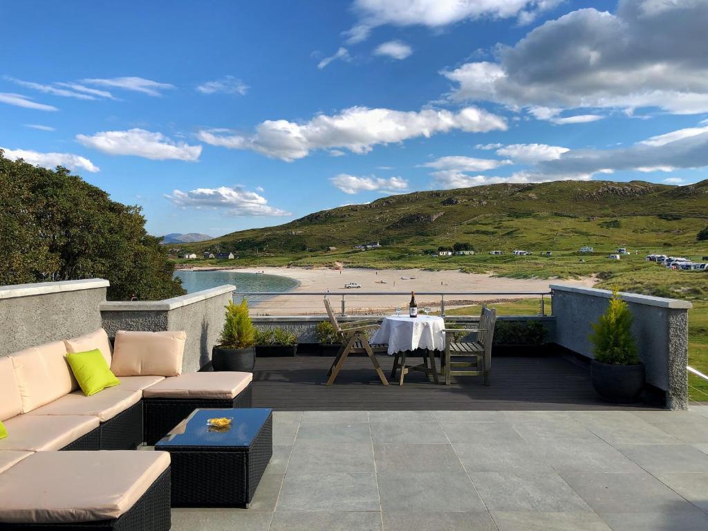 a patio with a table and chairs and a view of a beach at 3A Mellon Udrigle in Obinan