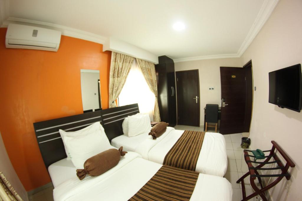 a hotel room with two beds and a television at Celia's Suites in Abeokuta
