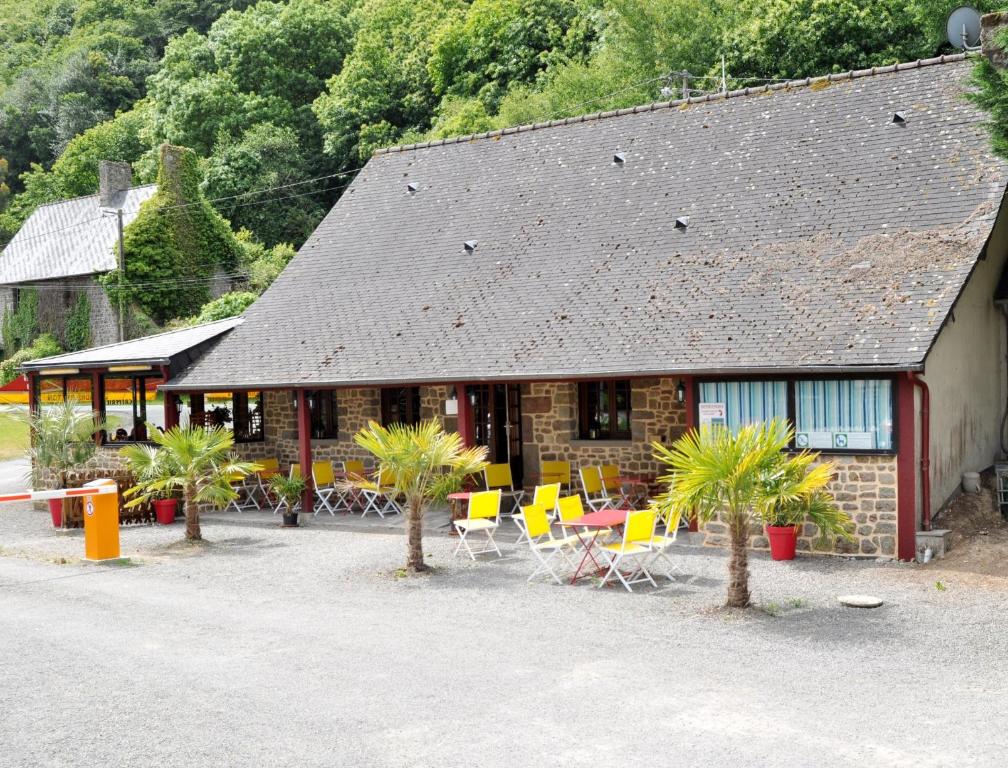 a building with chairs and palm trees in front of it at Camping Les Couesnons in Roz-sur-Couesnon