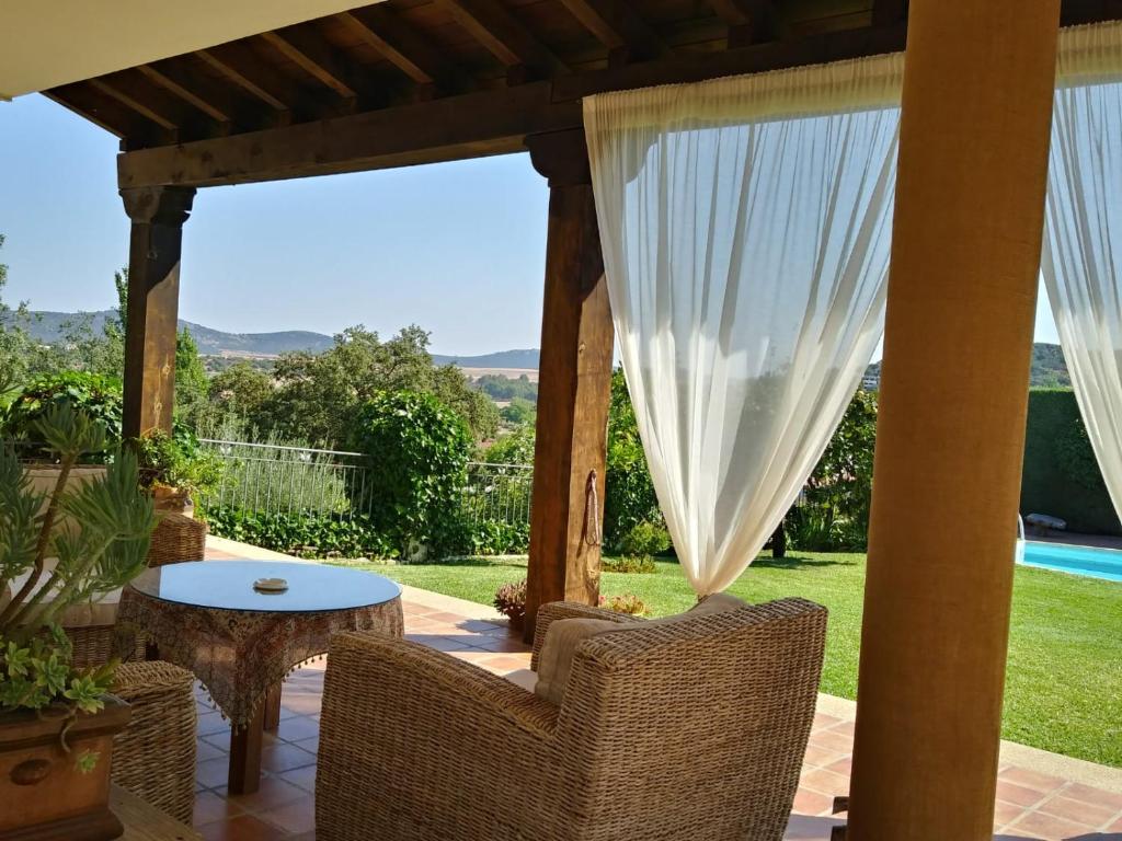 un patio con sillas de mimbre, mesa y piscina en Jardin de la Yedra, en Cáceres